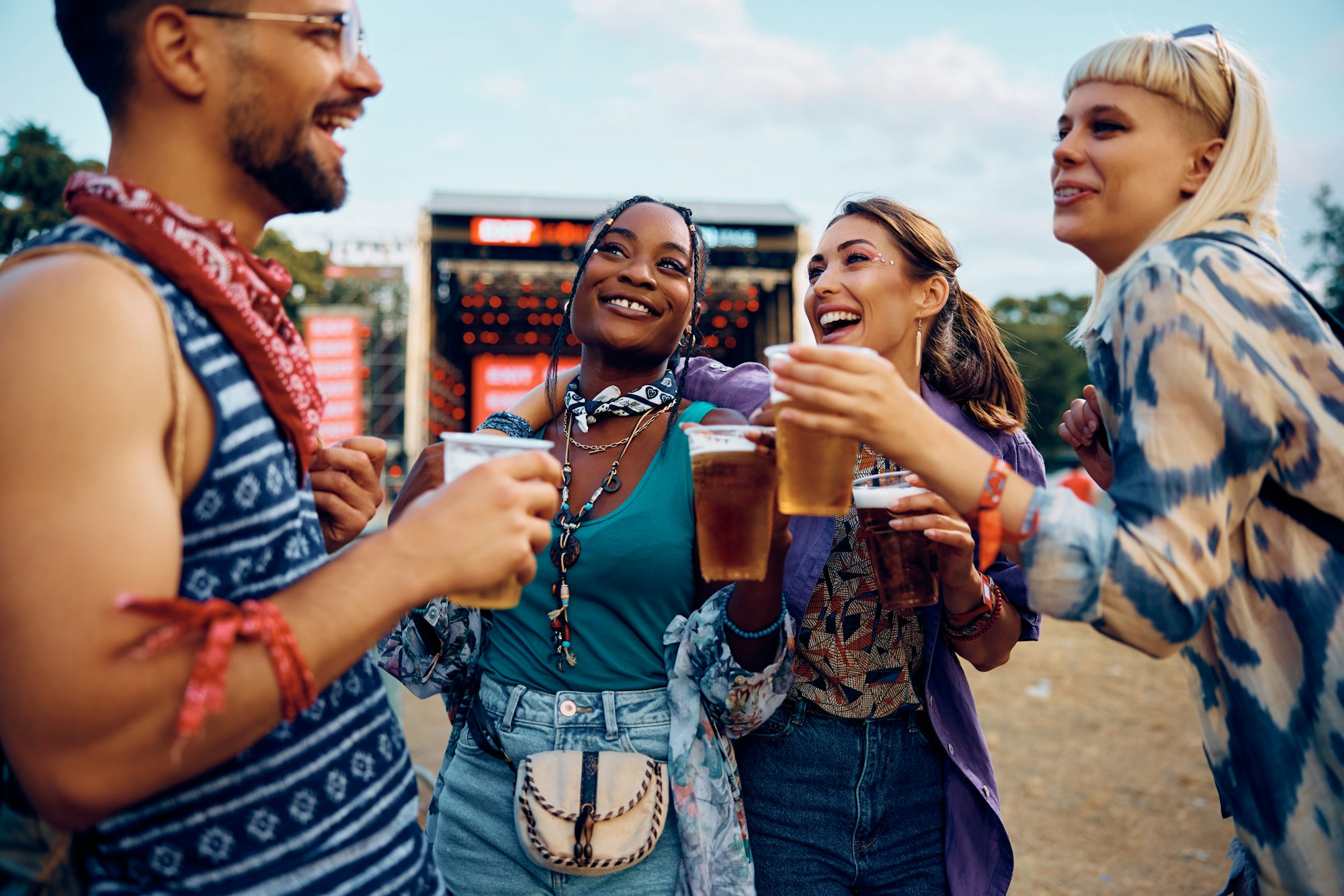 carefree-friends-having-fun-and-drinking-beer-in-front-of-music-stage-during-summer-festival-.jpg